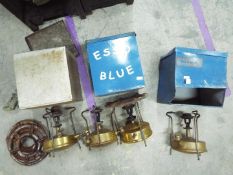 Four collectible brass kerosene camping stoves 3 in the original metal cases.