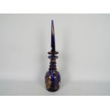 A blue glass decanter and stopper with hand painted floral and gilt decoration,