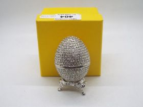 A crystal encrusted egg form trinket box with white enamel interior,