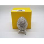 A crystal encrusted egg form trinket box with white enamel interior,