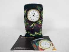 Moorcroft Pottery- a clock, tube lined and hand painted with finch and berries decoration,