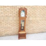 A contemporary longcase clock in light wood case, with architectural top,