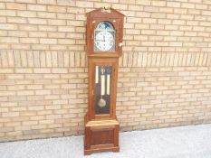 A contemporary longcase clock in light wood case, with architectural top,