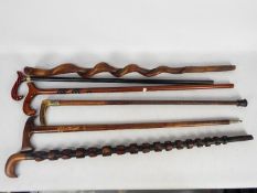 A collection of antique and later walking sticks including carved examples,