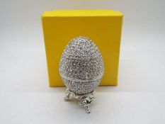 A crystal encrusted egg form trinket box with white enamel interior,