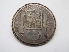 A 1792 8 Reales, Mexico mint, in white metal ropework mount and applied brooch pin.