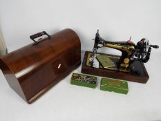 A Singer Sewing Machine in polished mahogany hood with functioning lock and key,
