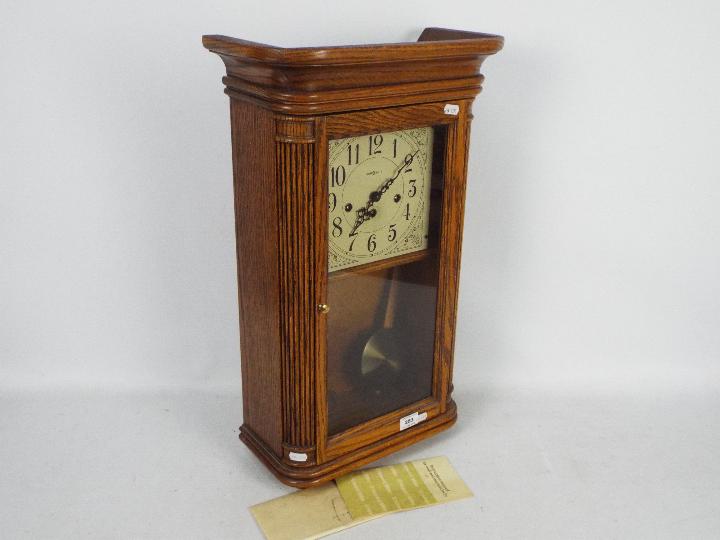 A Howard Miller light oak cased wall clock with key and pendulum. - Image 3 of 5
