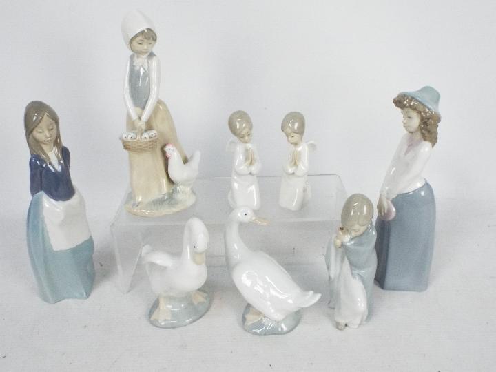 A collection of Lladro and Nao figures, largest approximately 24 cm (h).