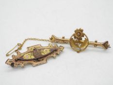 A 9ct gold bar brooch with floral decoration and safety chain and a further yellow metal brooch,