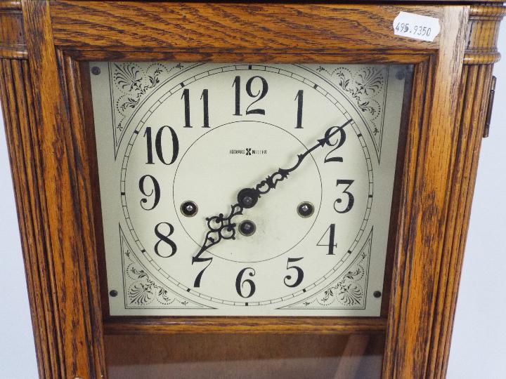 A Howard Miller light oak cased wall clock with key and pendulum. - Image 2 of 5