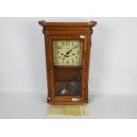 A Howard Miller light oak cased wall clock with key and pendulum.