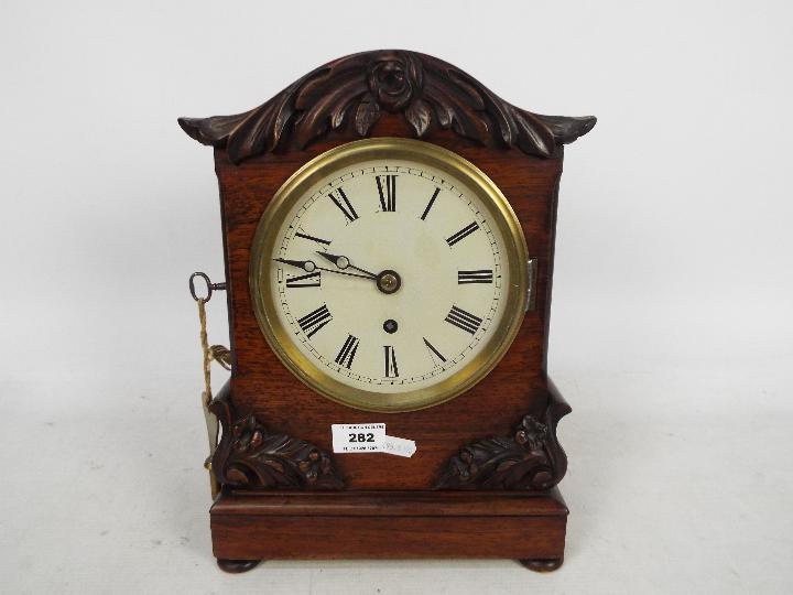 A mid-Victorian mantel clock, mahogany case with arched top and applied,