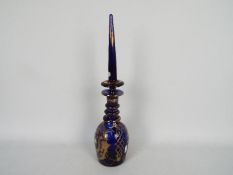 A blue glass decanter and stopper with hand painted floral and gilt decoration,