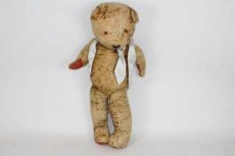 A large unmarked vintage teddy bear with jointed arms and legs. The golden bear stands approx.