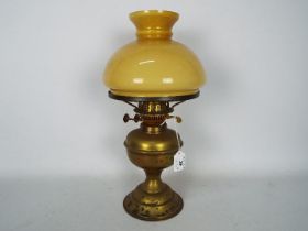 A vintage brass oil lamp with glass shad