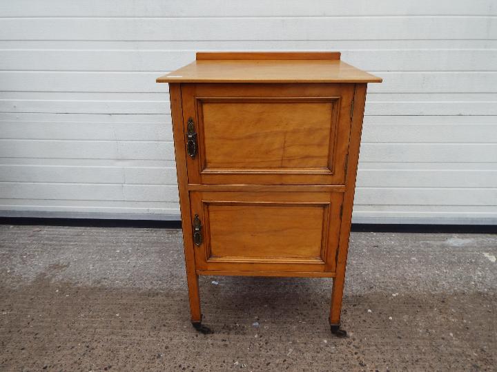 A twin door pot cupboard on castored supports, approximately 79 cm x 50 cm x 50 cm.