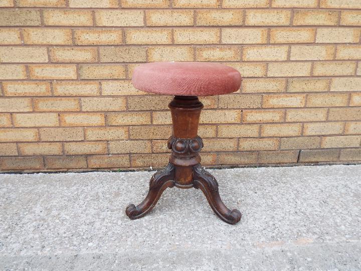 A rise and fall piano stool on carved tripod supports.