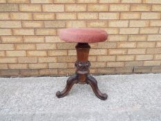 A rise and fall piano stool on carved tripod supports.