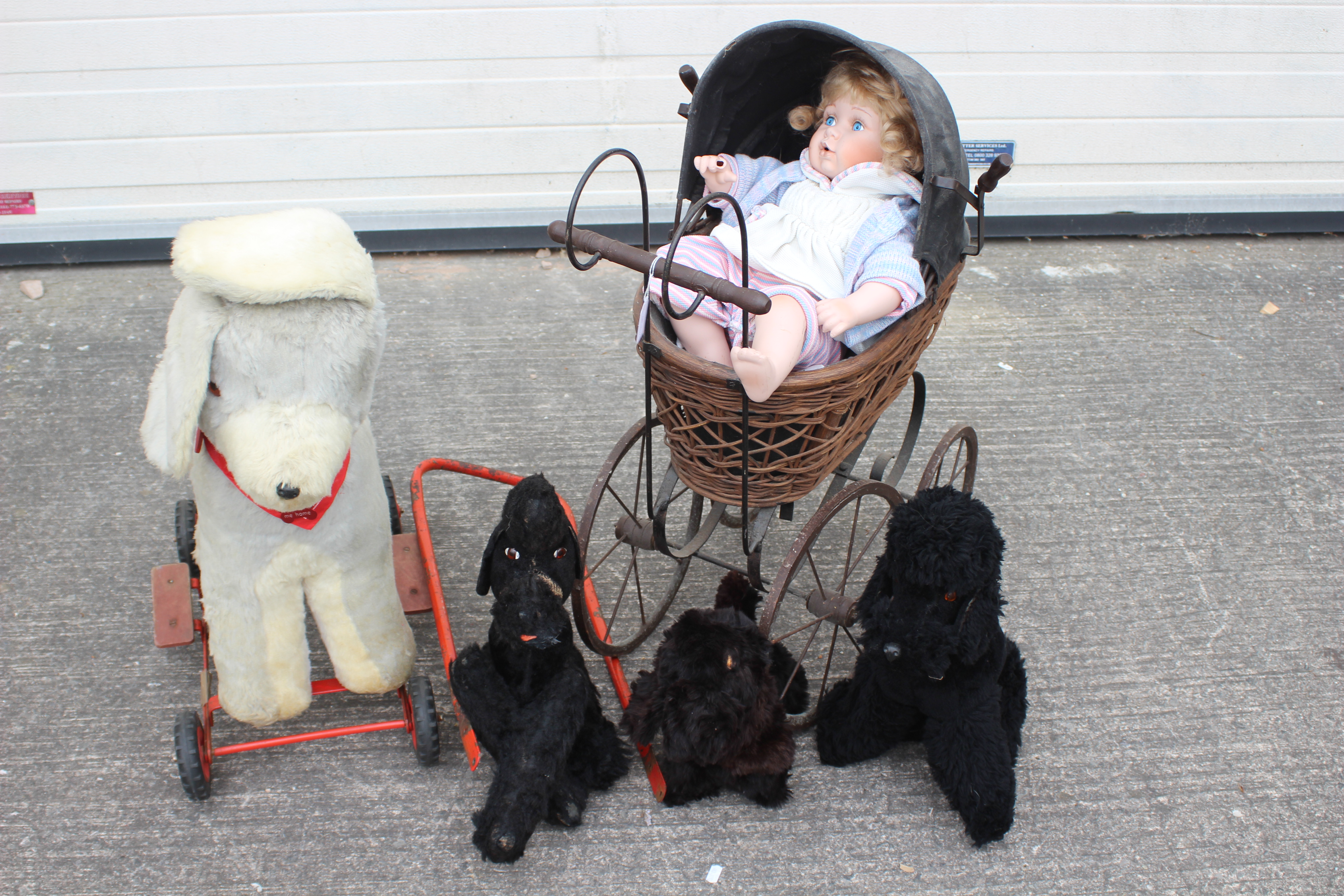 A group of vintage soft toys, a modern doll and ornamental Victorian styled pram.