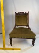 An upholstered chair with carved decoration on turned, castored supports.