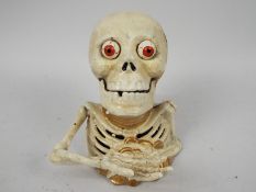 A cast iron money bank in the form of a skeleton.