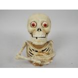 A cast iron money bank in the form of a skeleton.