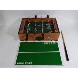 A wooden table top football game which can convert into a small snooker table and has a snooker cue.