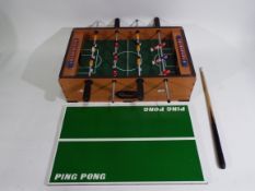 A wooden table top football game which can convert into a small snooker table and has a snooker cue.