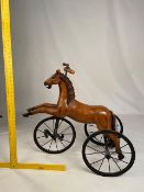 A child's carved wooden tricycle in the form of a horse, approximately 76 cm (h).