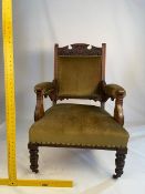 An upholstered armchair with carved decoration on turned, castored supports.