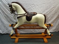 A vintage dapple grey rocking horse on trestle base, brown leather saddle, 112 cm (h),