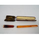 Two 9ct gold mounted cheroot holders contained in fitted cases, the larger case stamped pure amber,