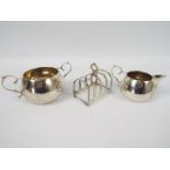 Silver items to include toast rack, cream jug and sugar bowl, varying assay and date marks,