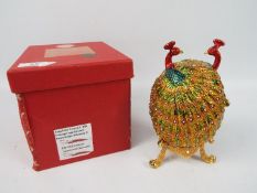 A large enamel and crystal encrusted trinket box of ovoid form depicting a pair of peacocks,