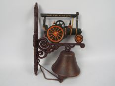 A wall mountable, cast iron bell with traction engine decoration.