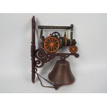 A wall mountable, cast iron bell with traction engine decoration.