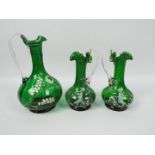 A pair of Mary Gregory green glass jugs and one larger example, largest approximately 21 cm (h).