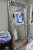 Rectangular ornate silvered framed bevelled wall mirror, 203cm by 102cm.