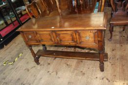 Oak dresser having two central cupboard doors flanked by two drawers raised on turned legs joined