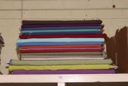 Seventeen rolls of mostly plain fabric of varying lengths.