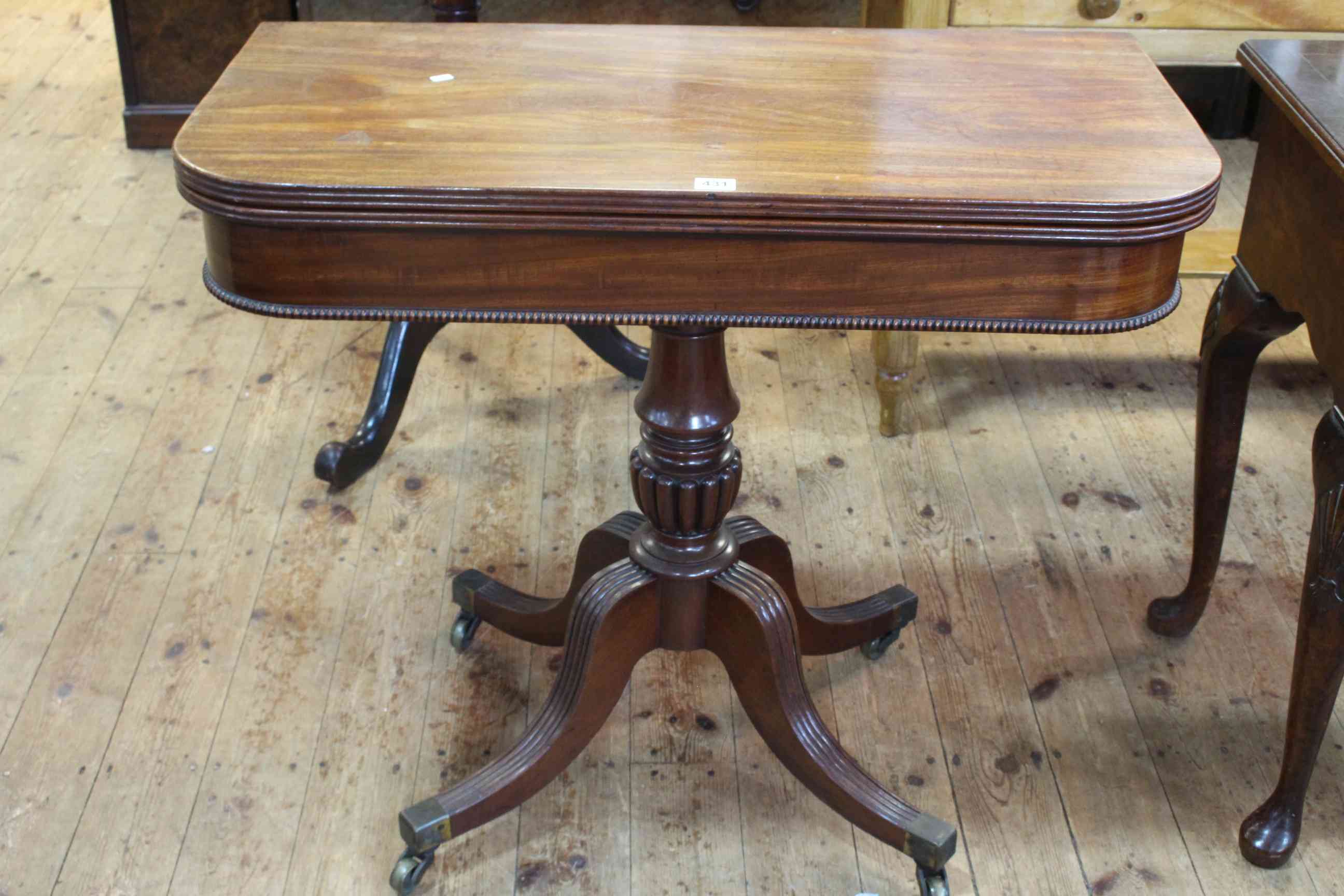 19th Century mahogany fold top tea table on turned pedestal to four reeded scrolled legs,