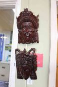 Two carved wooden mask wall hangings, 27cm high.