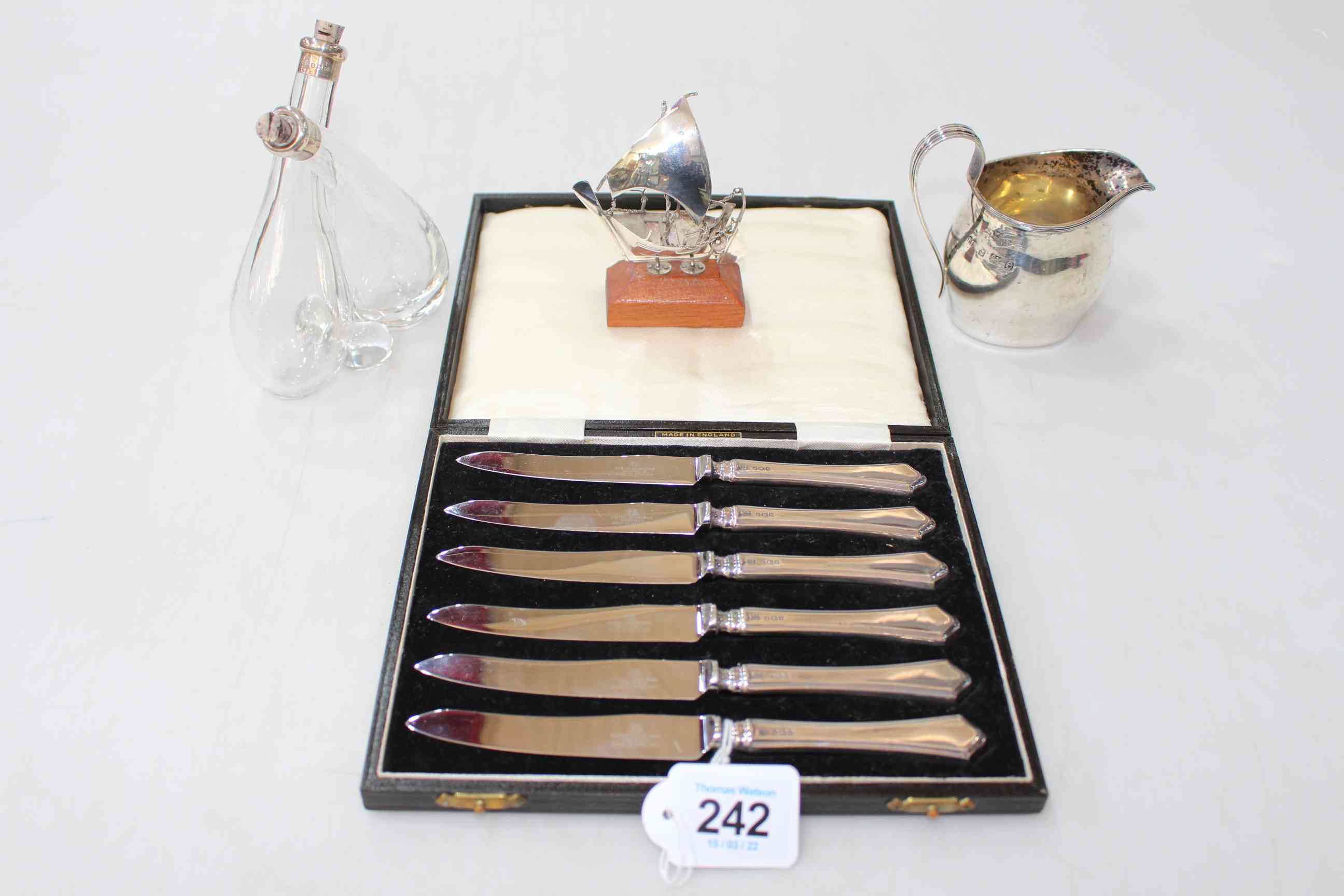 Cased silver handled tea knives, silver cream jug, silver mounted vinegar bottle,