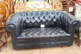 Black leather deep buttoned two seater Chesterfield settee.