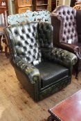 Bottle green buttoned leather wing armchair.