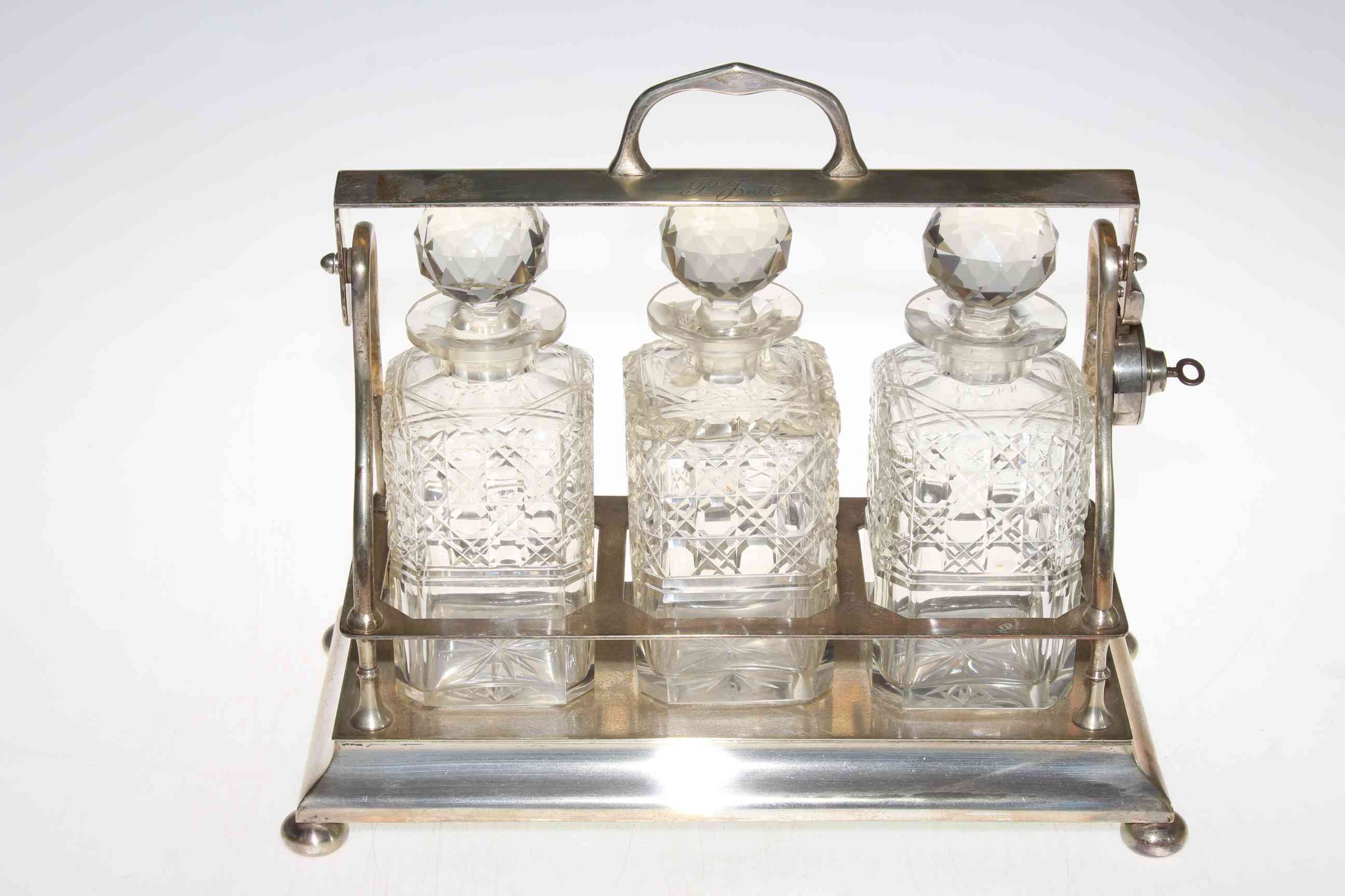 EPNS three bottle tantalus with crystal decanters (with key).