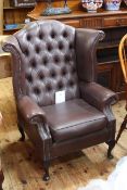 Brown deep buttoned and studded wing armchair.