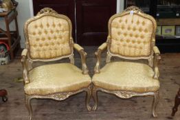 Pair part gilt painted French style fauteuils in gold patterned buttoned fabric.