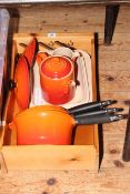 Three Le Creuset pans and lids, casserole dish, teapot, cream jug and wood crate.